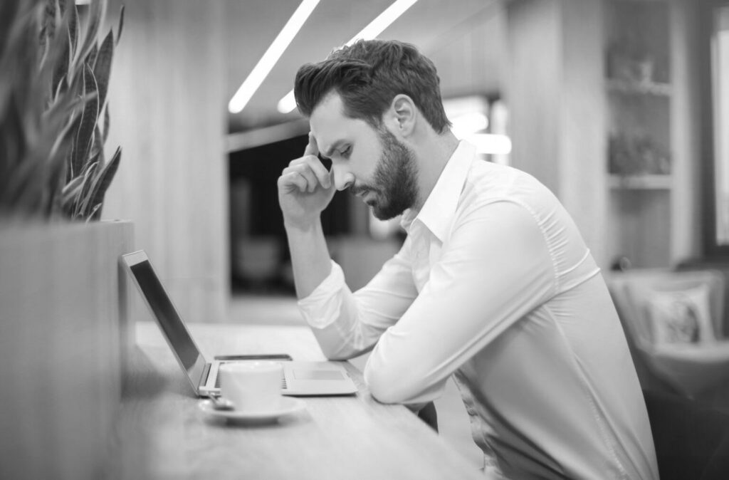 Un homme au bureau, devant son ordinateur, qui semble être stressé.